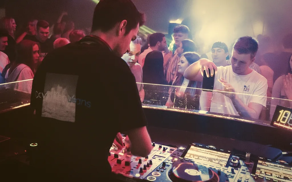 DJ Max Didczilatis im Club mit Teal-Lichtstrahlen DJ Max Didczilatis im Club mit Teal-Lichtstrahlen