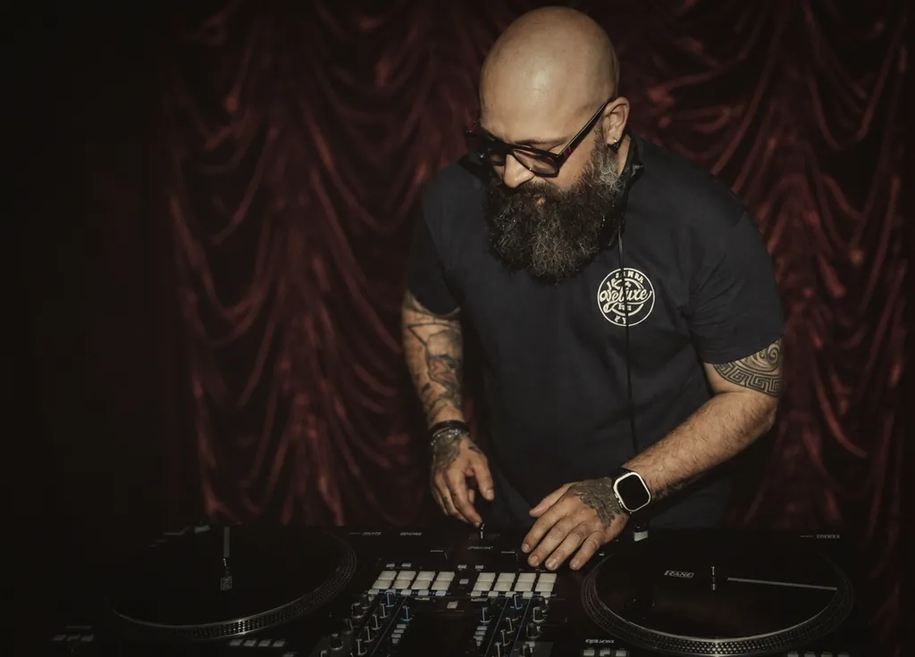 DJ Janni de Luxe vor burgunderrotem Samtvorhang am DJ-Pult, theatralische Stimmung DJ Janni de Luxe vor burgunderrotem Samtvorhang am DJ-Pult, theatralische Stimmung