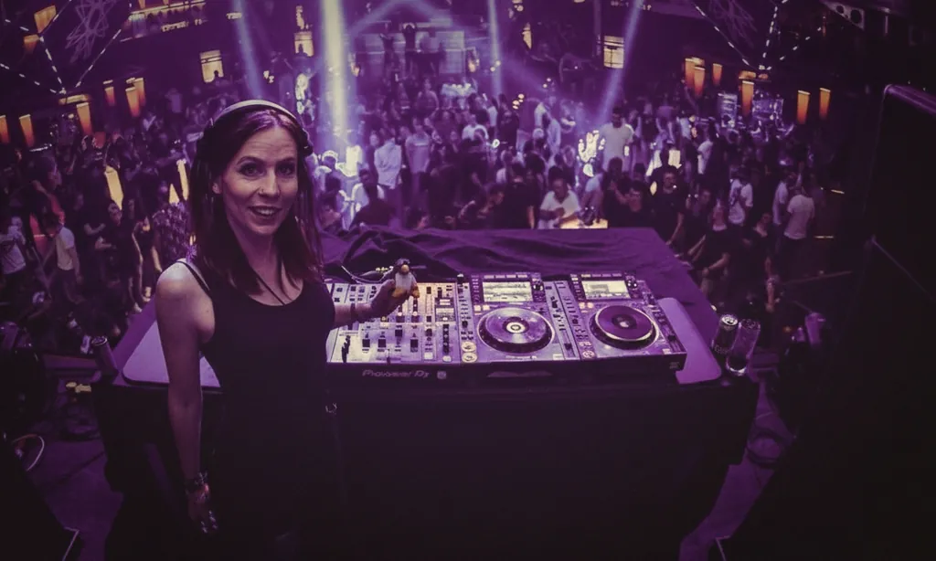 Sabrina Blömer am DJ-Pult mit voller Tanzfläche und Lichtfächern im Hintergrund