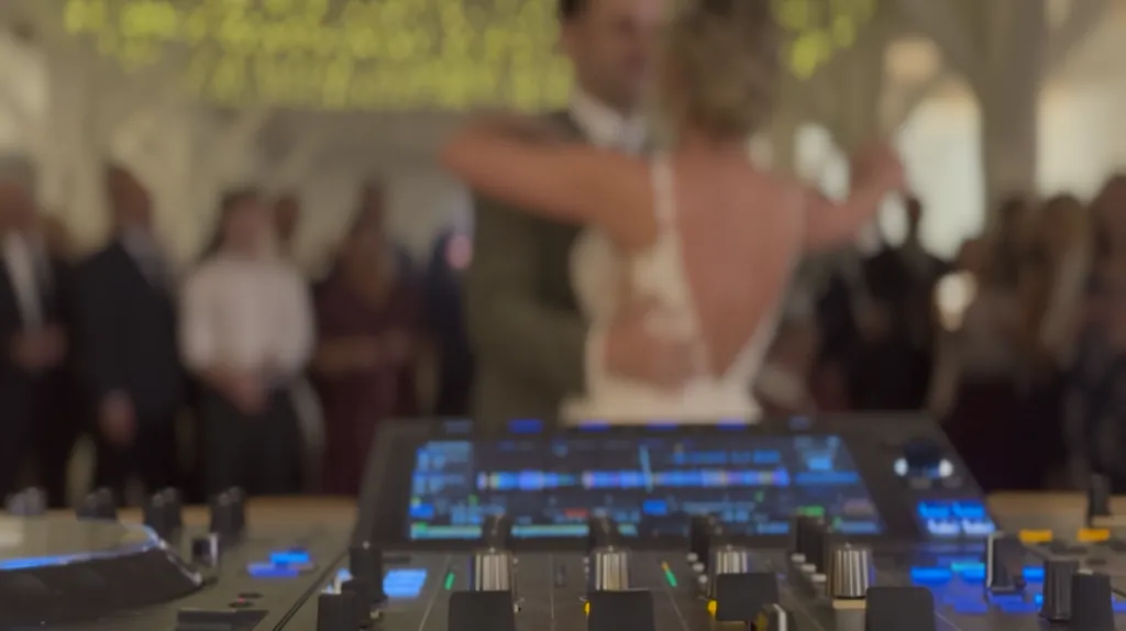 Brautpaar beim Hochzeitstanz, DJ-Pult mit dezenter Lichtshow im Hintergrund