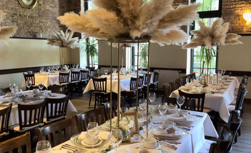 Restaurant Cosacks Brennerei Lippstadt mit eingedeckten Hochzeitstafeln, hohen Pampasgras-Arrangements im Boho-Stil, Backsteinwänden und Tageslichtfenstern Restaurant Cosacks Brennerei Lippstadt mit eingedeckten Hochzeitstafeln, hohen Pampasgras-Arrangements im Boho-Stil, Backsteinwänden und Tageslichtfenstern